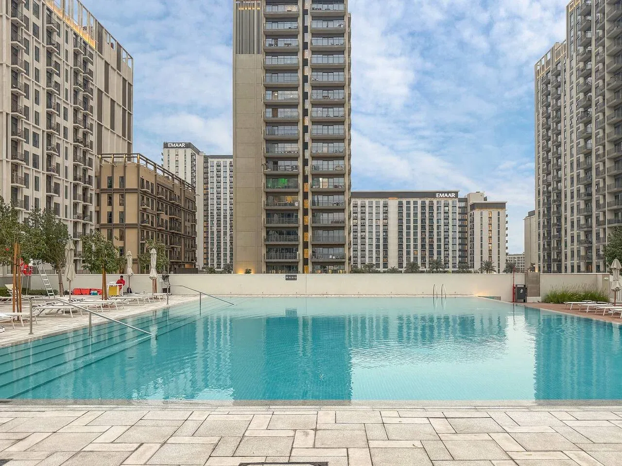An outdoor swimming pool sits among tall residential buildings.