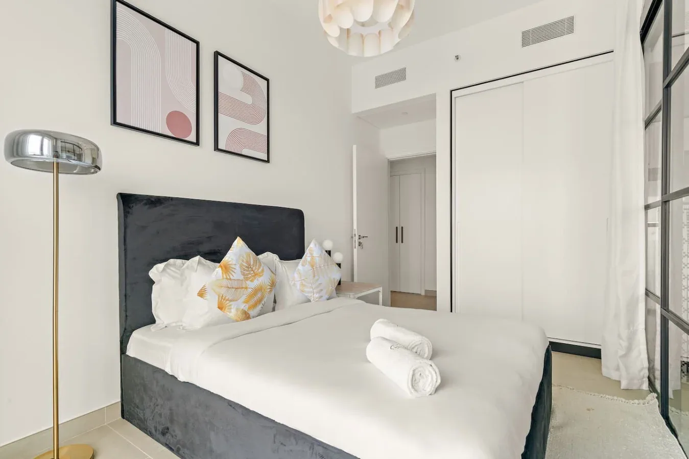 A bright bedroom with a made bed and framed artwork on the wall.