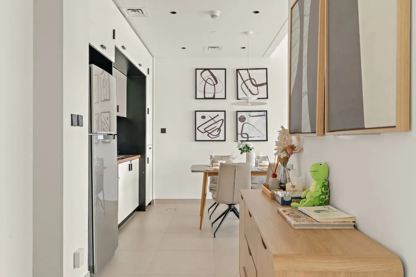 A bright dining area with a table beneath four abstract framed artworks.