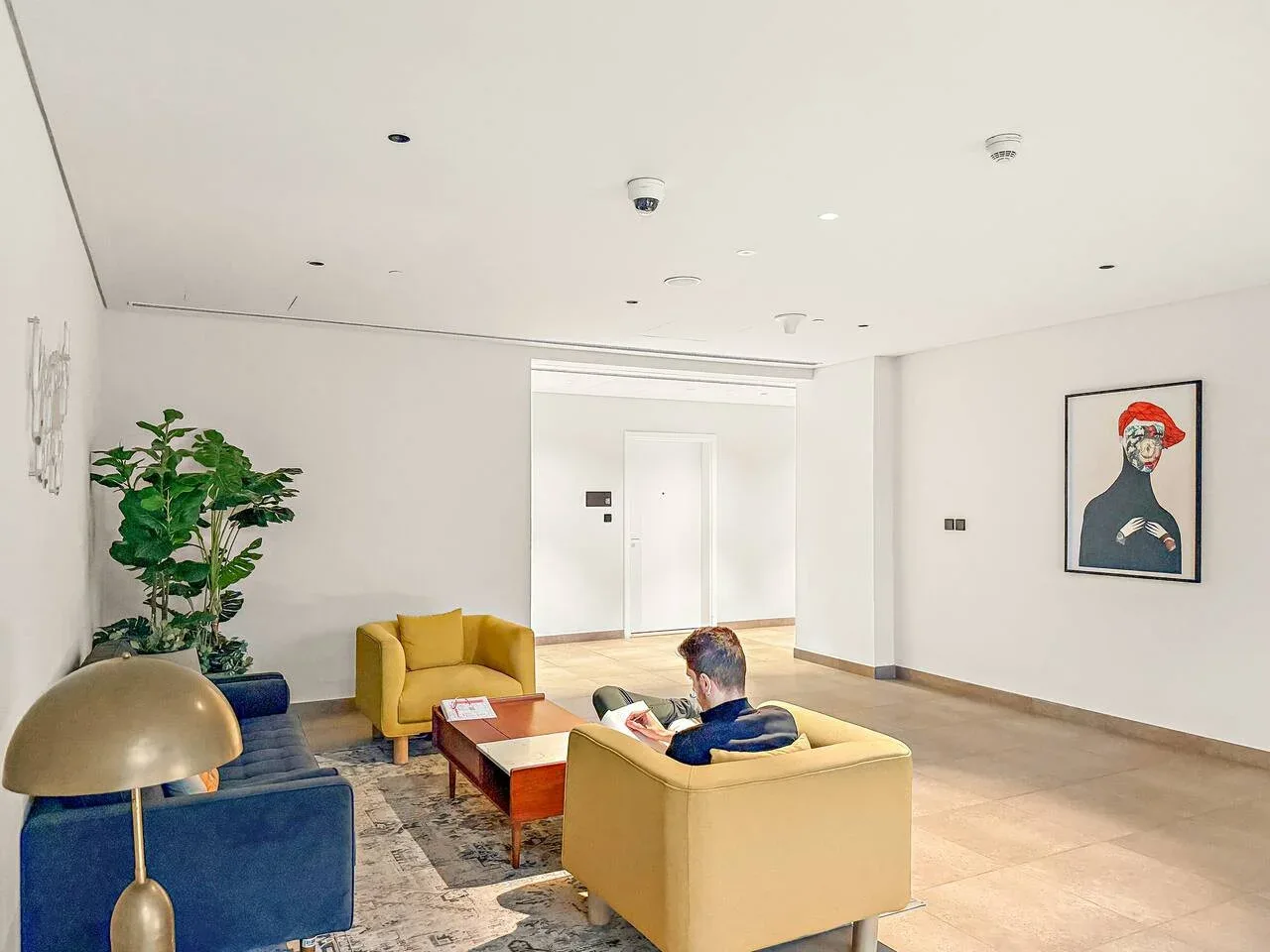 A bright living room with colorful seating, a coffee table, and framed artwork.