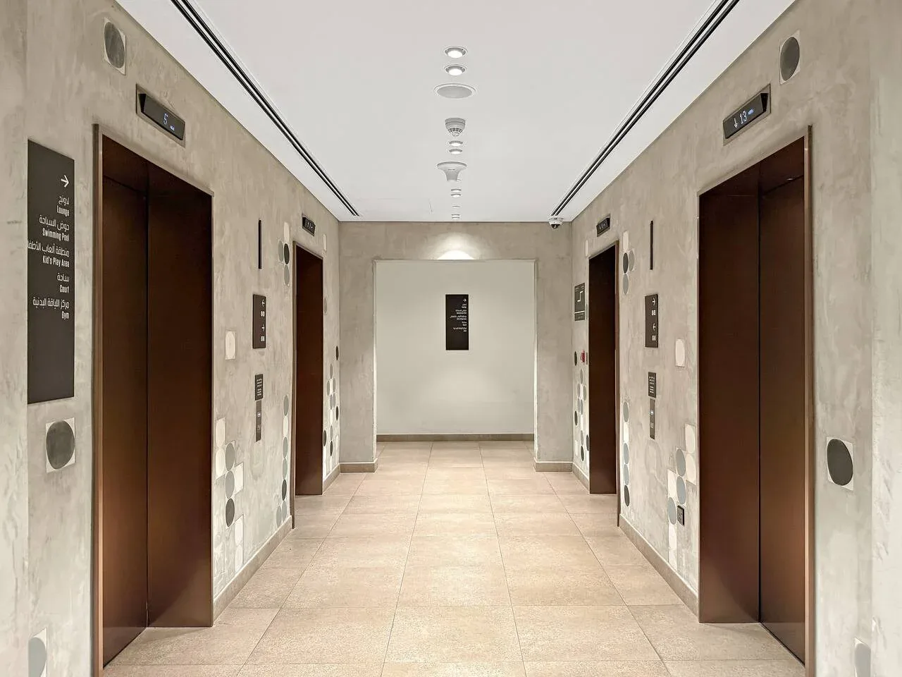 An elevator lobby with several elevator doors along a tiled hallway.