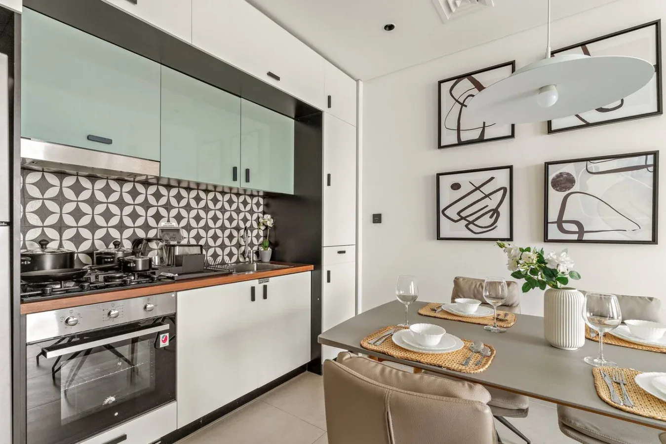 A modern kitchen and dining area with patterned backsplash and framed artwork.