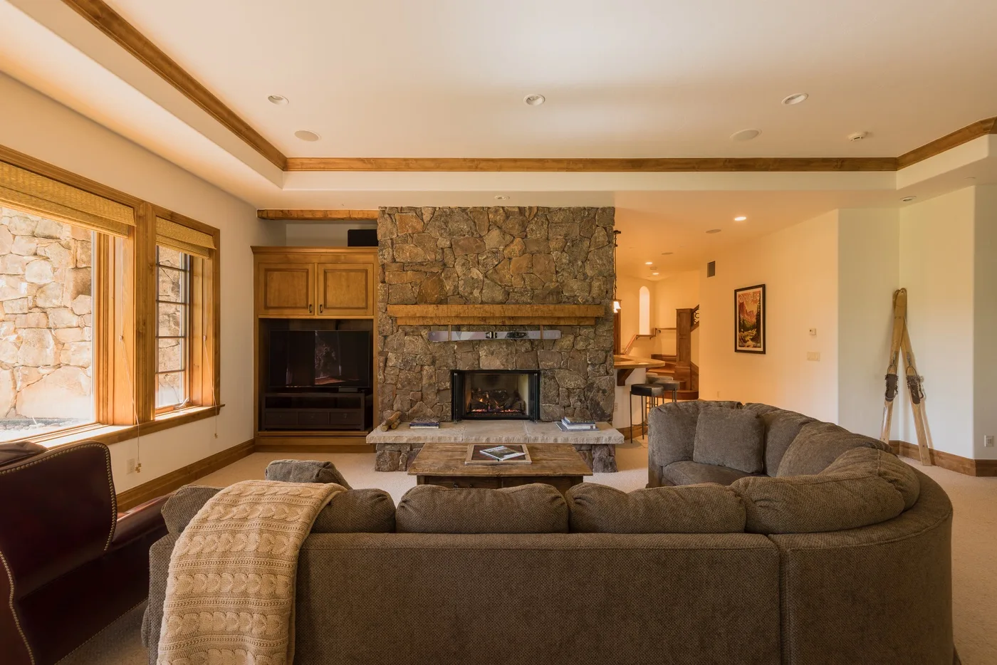 A living room with seating arranged around a stone fireplace and television.