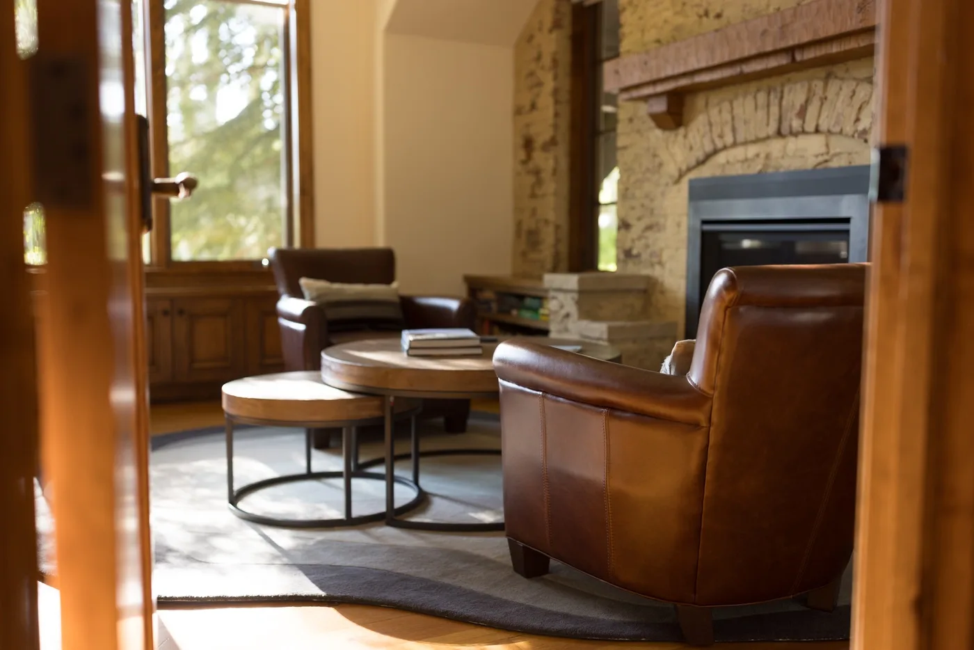 A living room with brown seating and a stone fireplace.