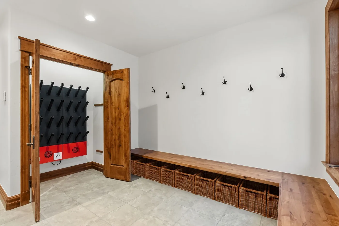 A mudroom with wall hooks and a long wooden bench with woven baskets.