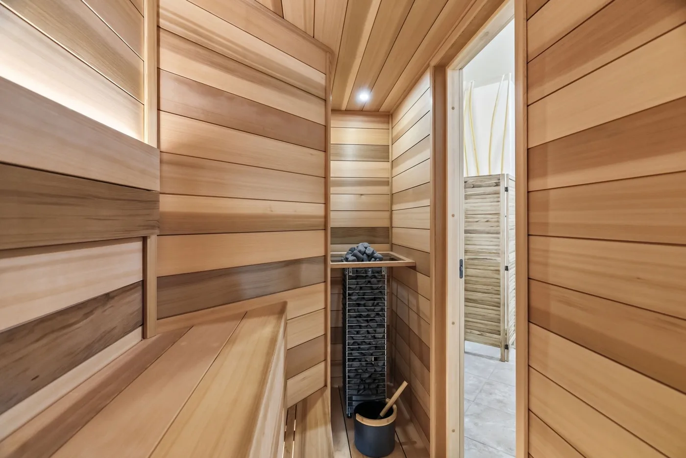 A wood-paneled sauna with tiered seating and a heater.