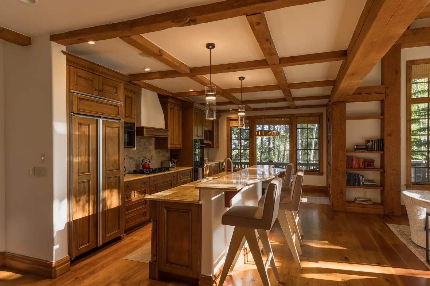 A wood-paneled kitchen and dining area with a central island and overhead beams.