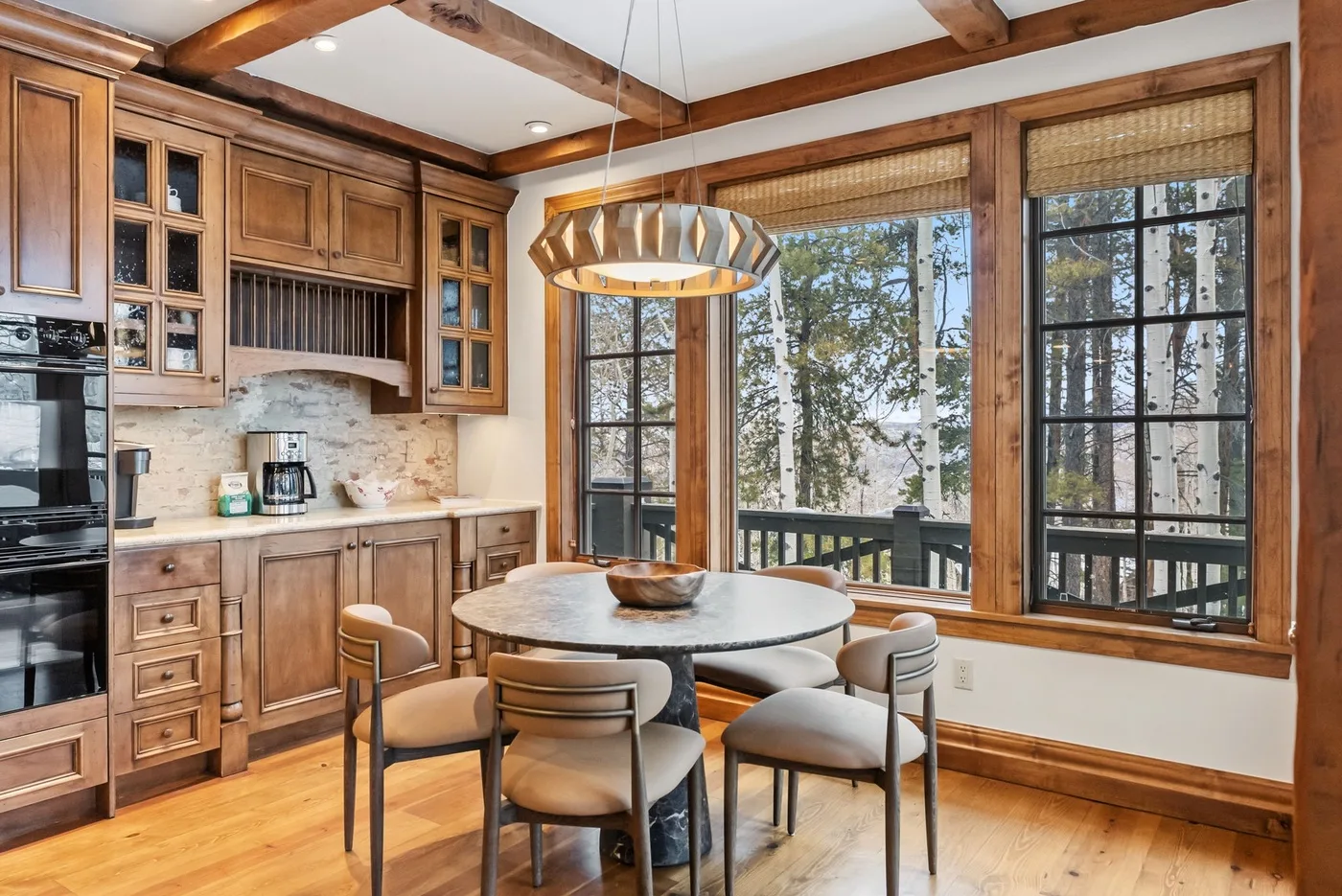 A kitchen dining area with a round table beside large windows.