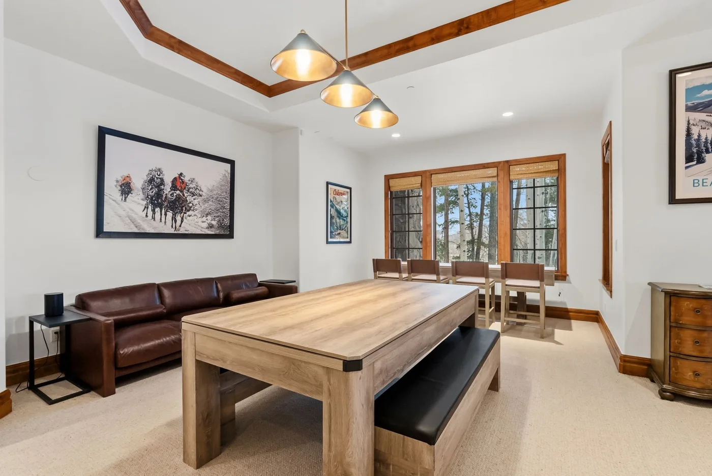A bright dining room with a large wooden table and seating beneath pendant lights.