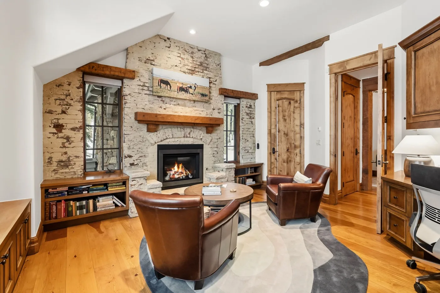 A living room with leather seating, a fireplace, and a wooden floor.