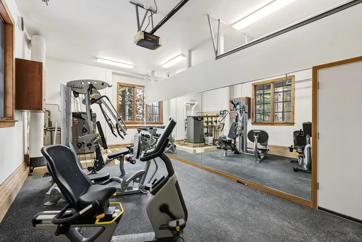 A gym with exercise machines and a wall-length mirror.