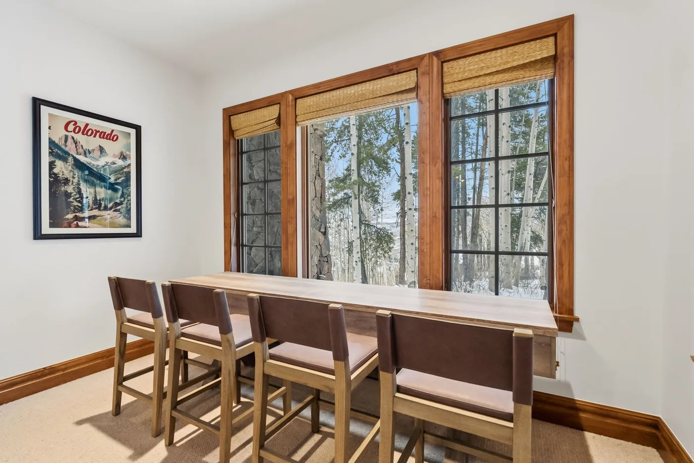 A dining area with a long table and seating beside large windows.