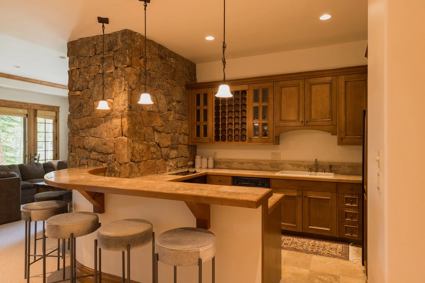 A warm kitchen and bar area features wooden cabinetry and a stone column.
