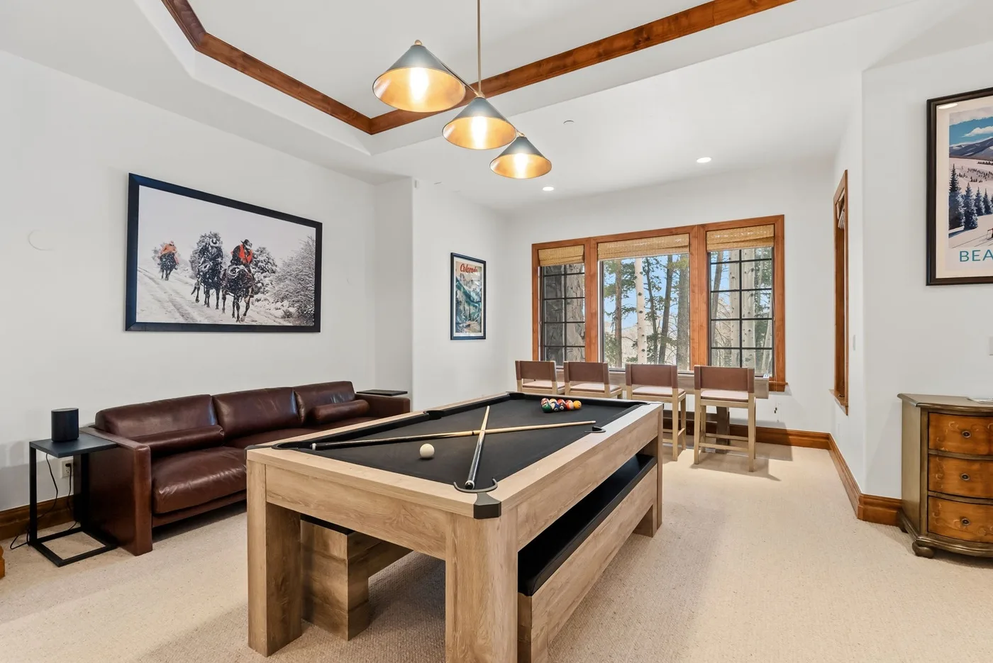 A bright game room features a pool table, seating, and large windows.