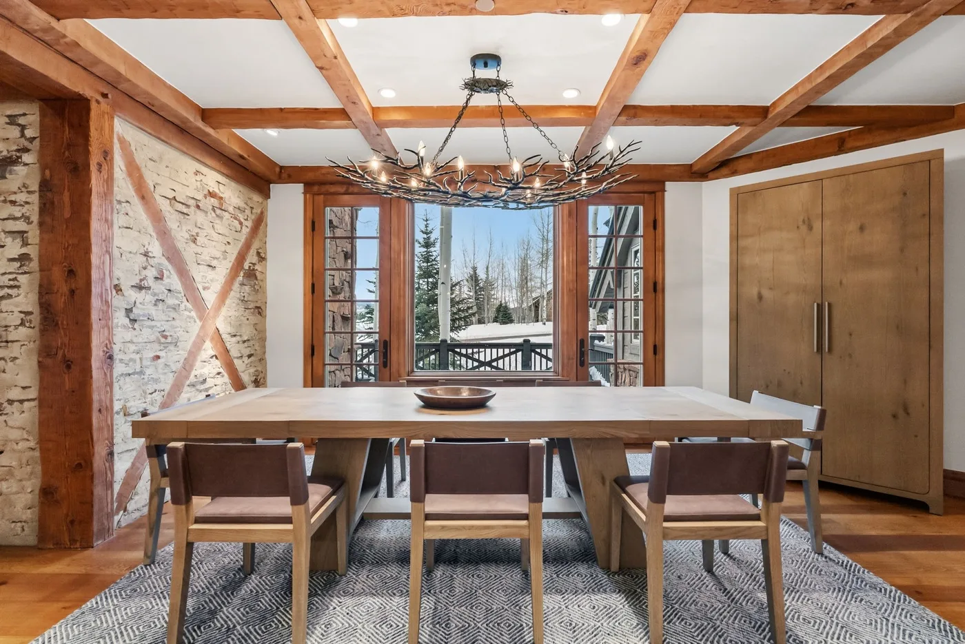 A dining area with a long table and windows overlooking a snowy landscape.