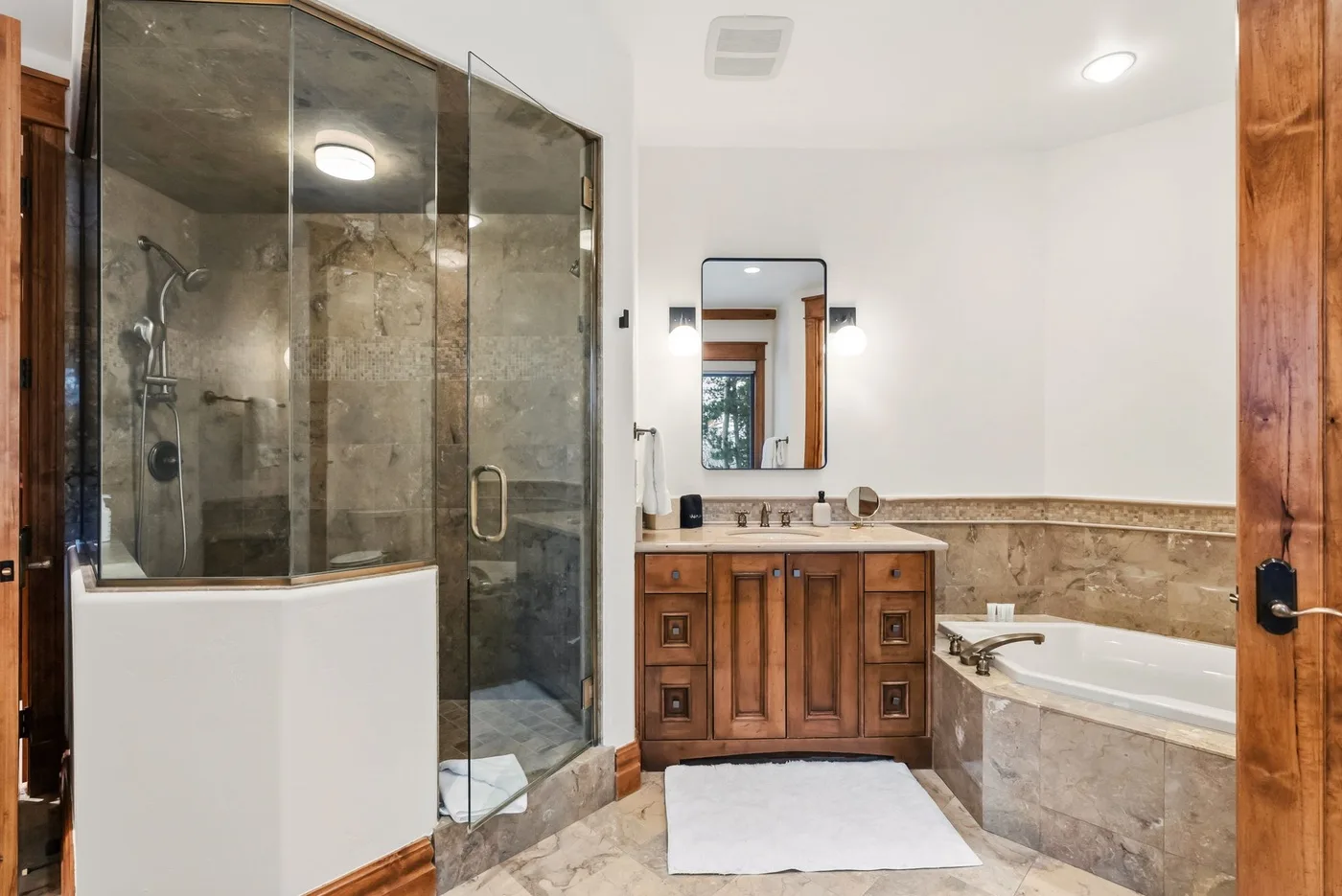 A bathroom with a glass-enclosed shower, vanity, and bathtub.
