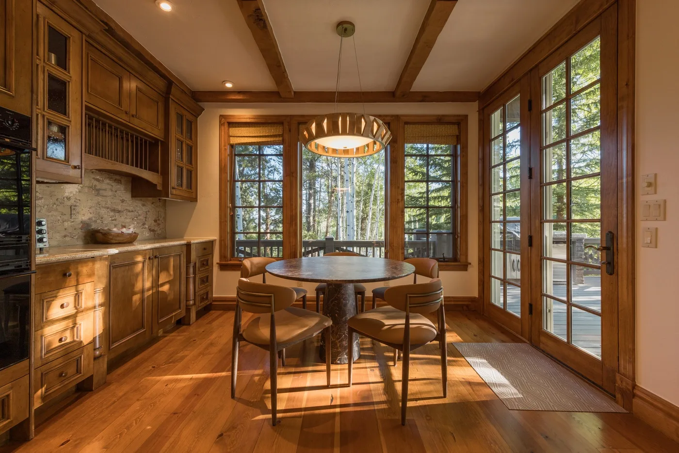 A wood-paneled kitchen and dining area with a round table beside large windows.
