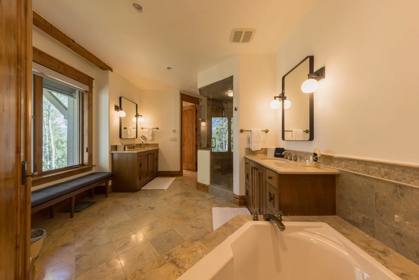 A spacious bathroom with a bathtub, vanity, and large windows.