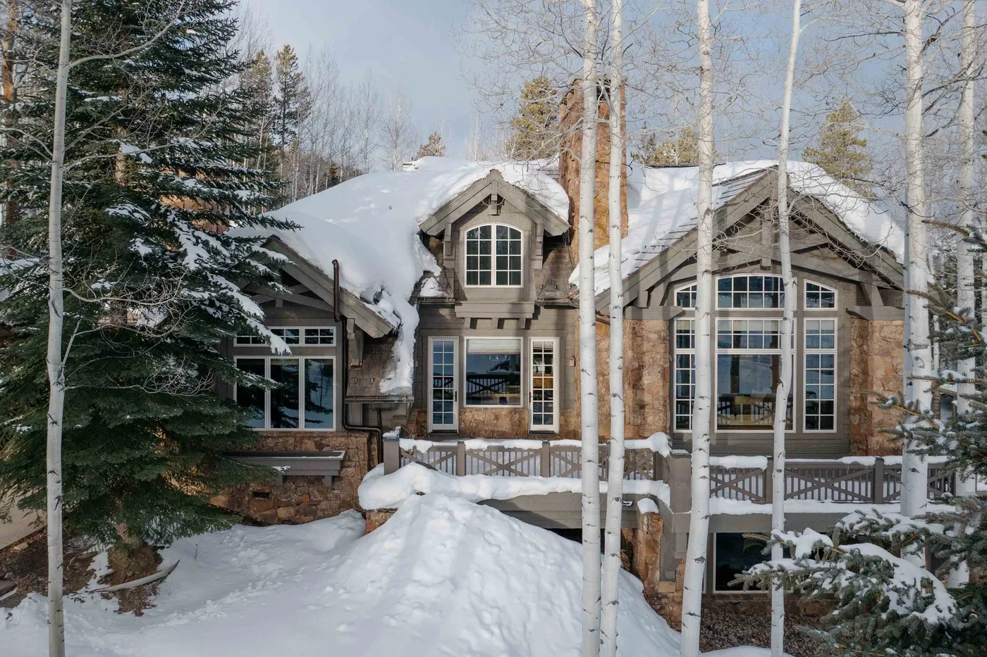 A large house stands among snow-covered trees in a winter landscape.