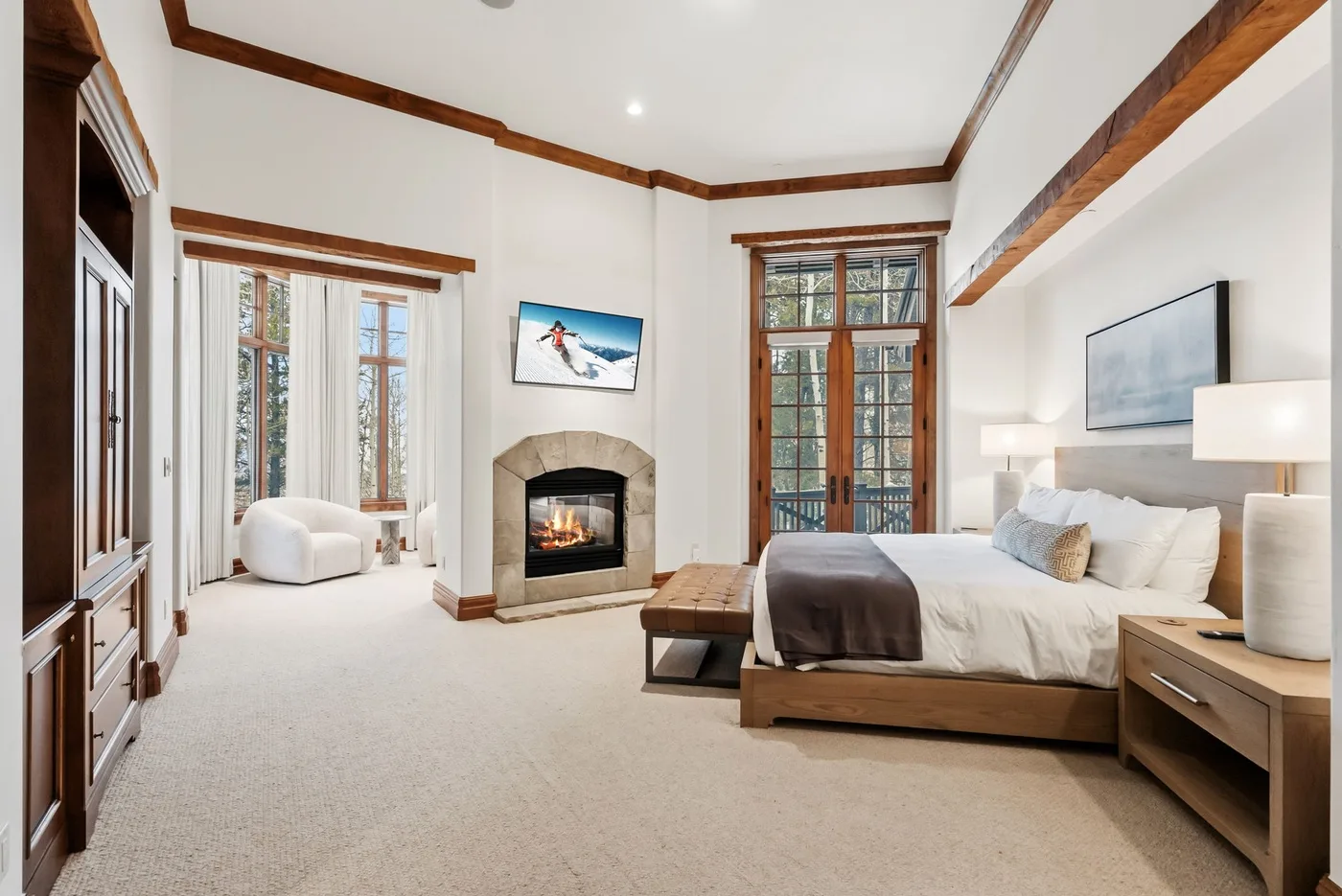 A spacious bedroom with a large bed, a fireplace, and tall windows.