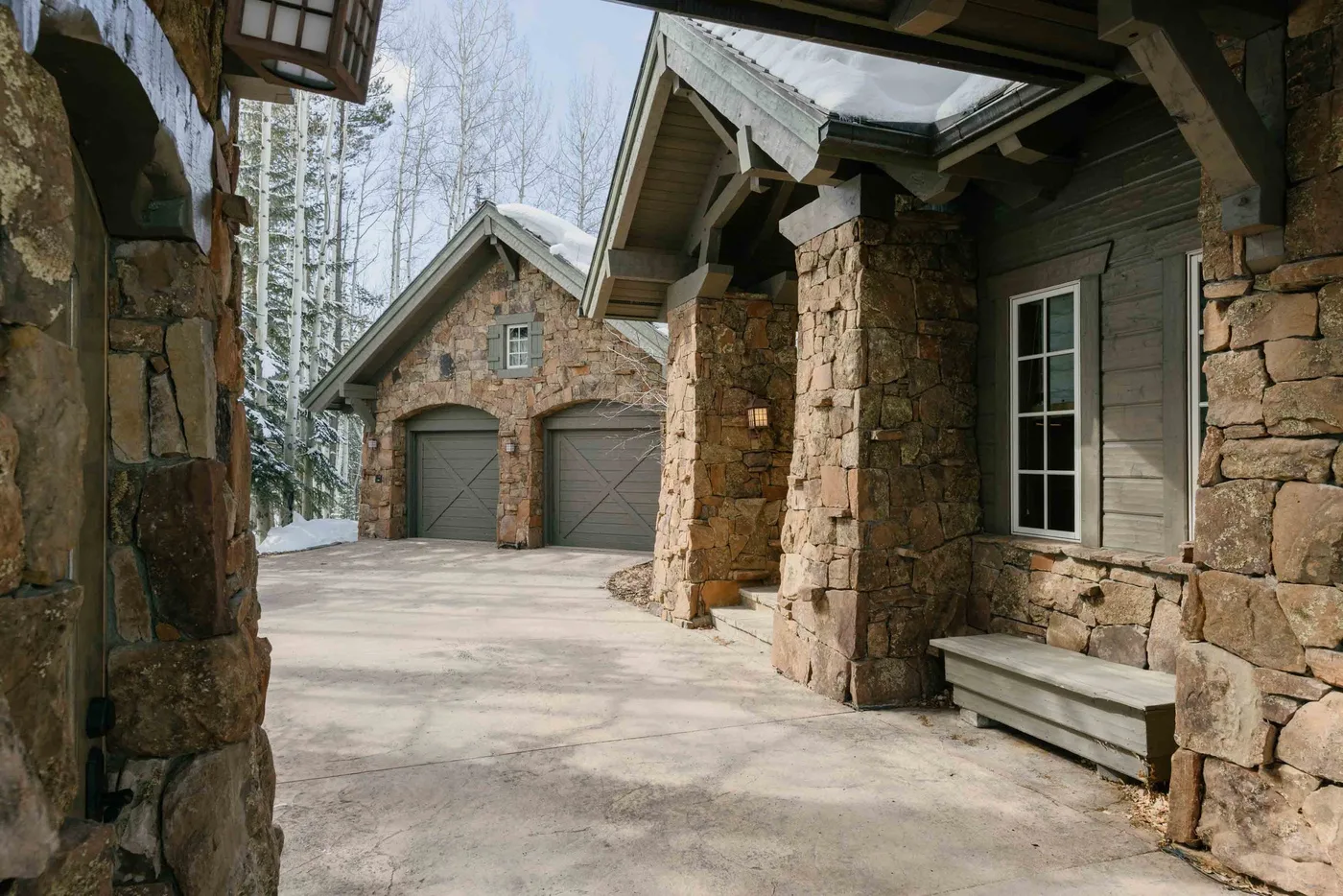 A stone building entrance beside a broad paved driveway and two garage doors.
