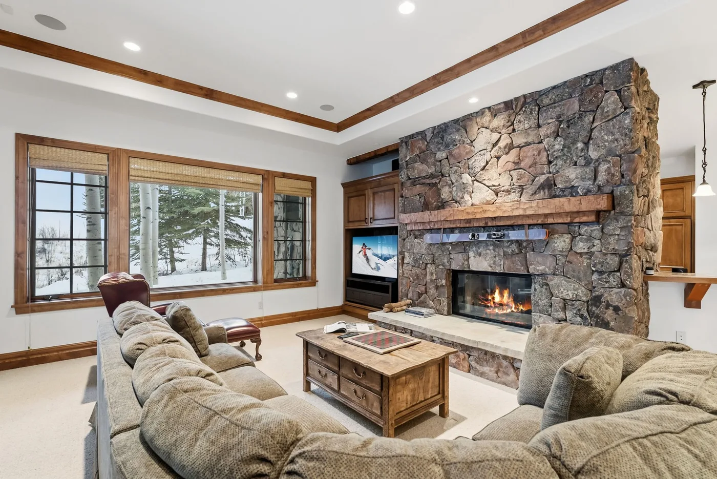 A living room with a stone fireplace and seating arranged around a coffee table.
