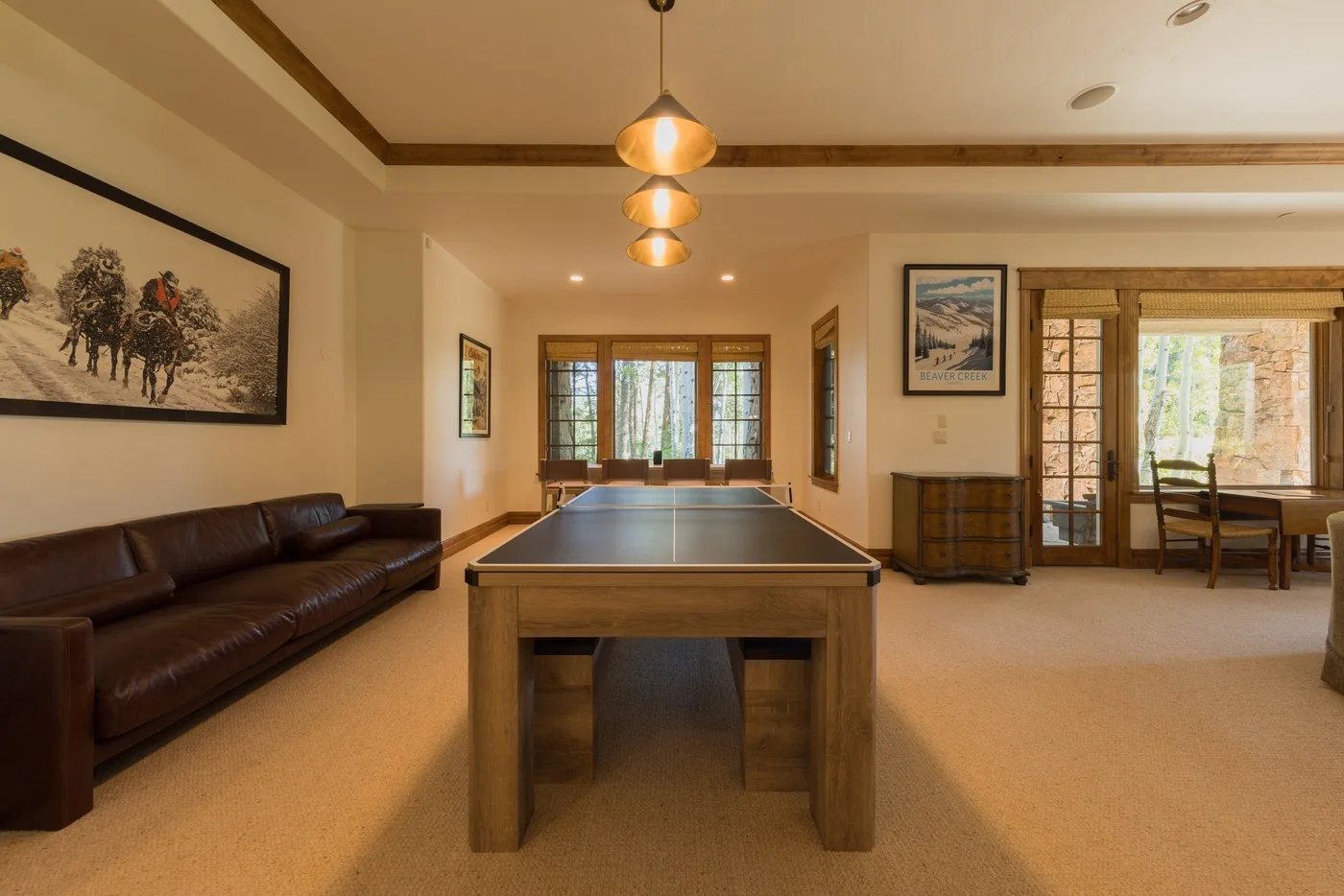A recreation room with a pool table, leather seating, and windows.
