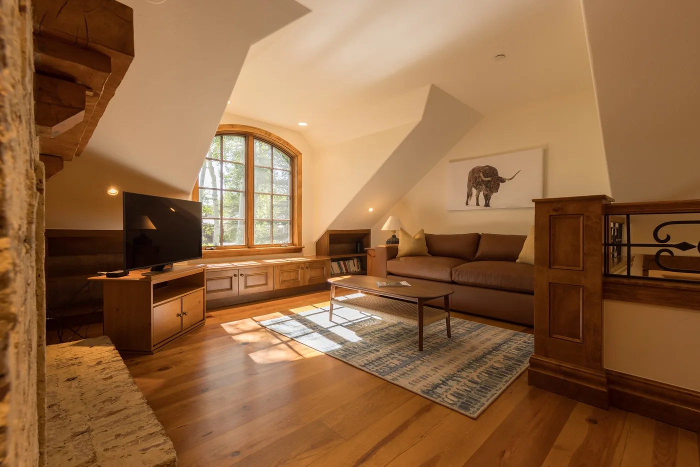 A living room with seating, a television, and a large arched window.