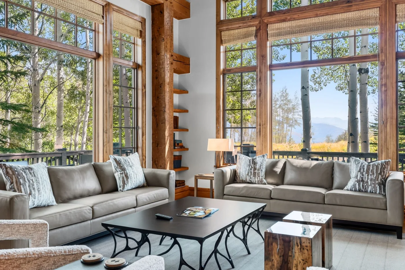 A living room with seating and a coffee table beside large windows.