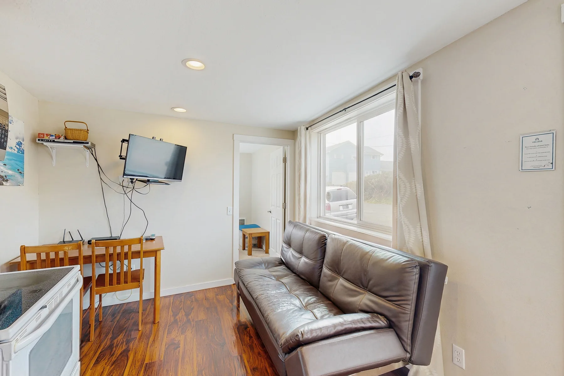 A living room with seating beside a large window and a small dining table.