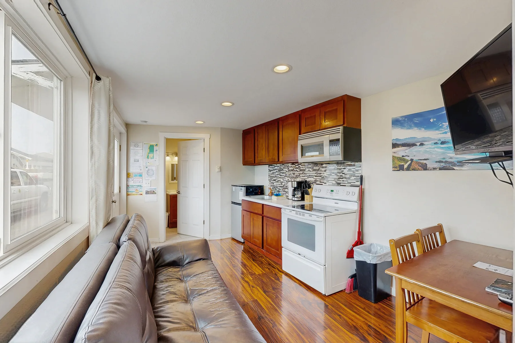 A compact kitchen and dining area with wood cabinets and a table beside the seating.