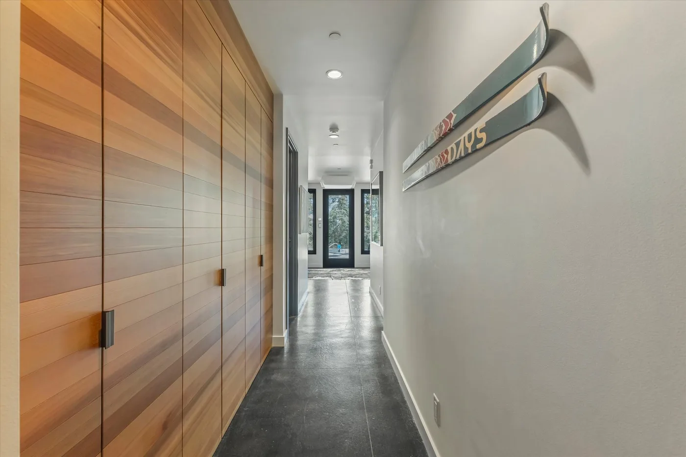 A hallway with wooden cabinetry along one wall and a dark tiled floor.