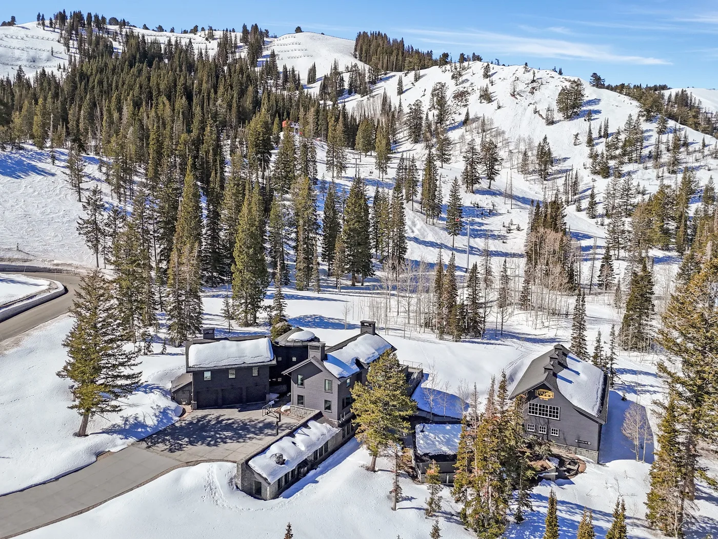 A cluster of buildings sits among snowy hills and evergreen trees.