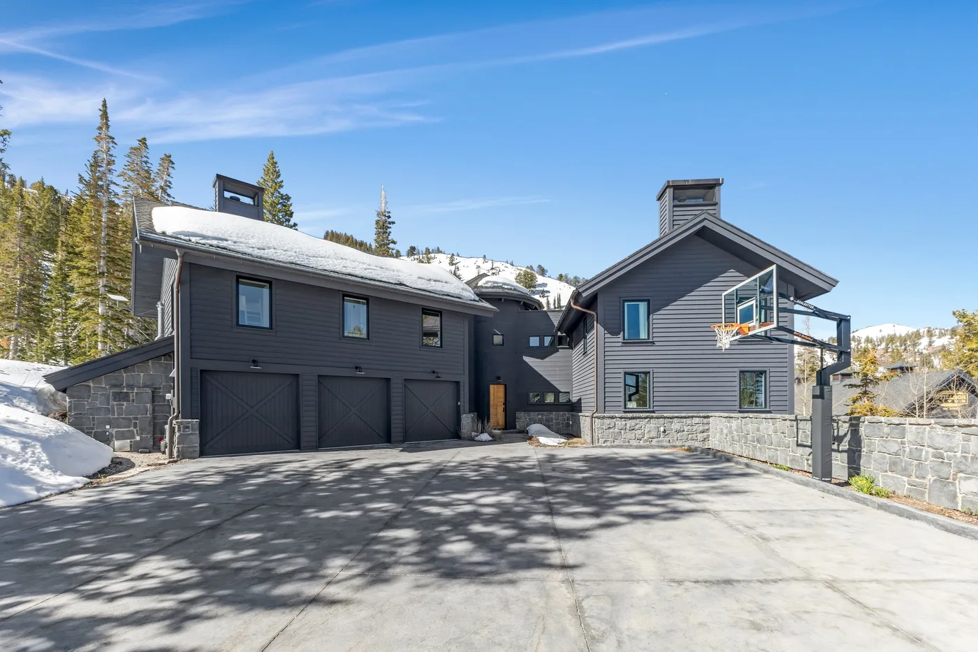 A large gray house with a driveway and a basketball hoop.