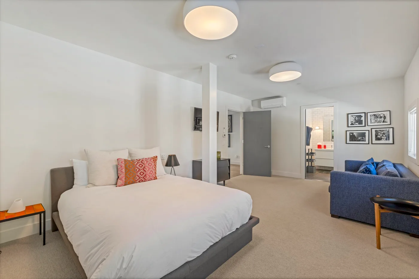 A bedroom with a large bed and a seating area beside it.