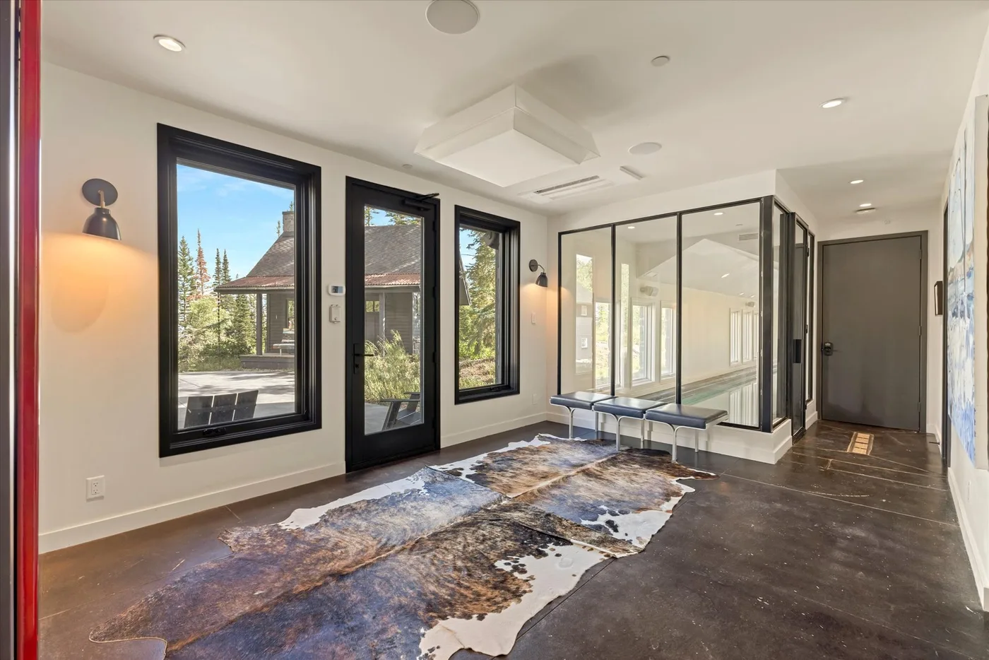 Bright interior room with large windows, glass partitions, and a patterned floor covering.