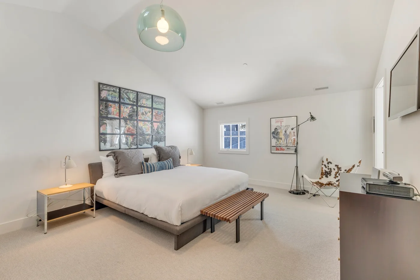 A bright bedroom with a bed, a window, and a seating area.