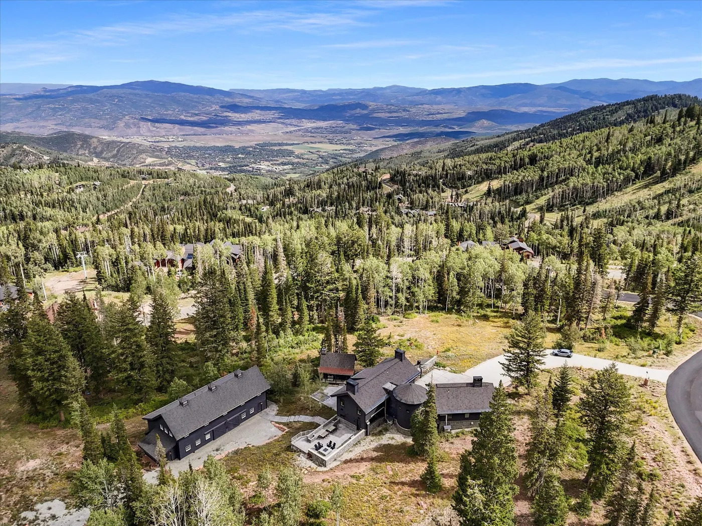 A mountain lodge sits among pine trees overlooking a broad valley.