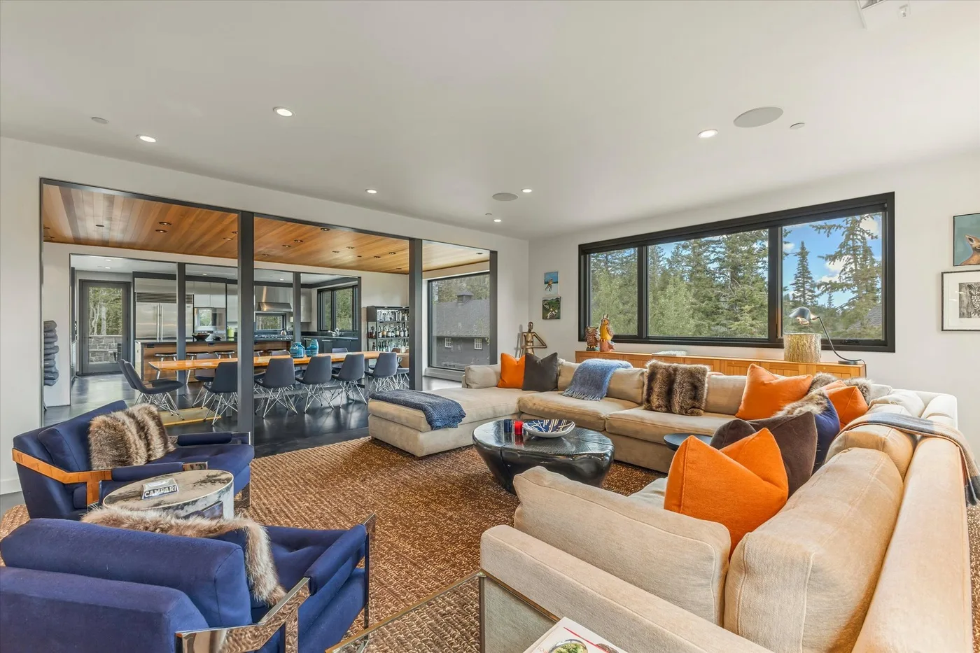 A living room with seating arranged around a coffee table and large windows.