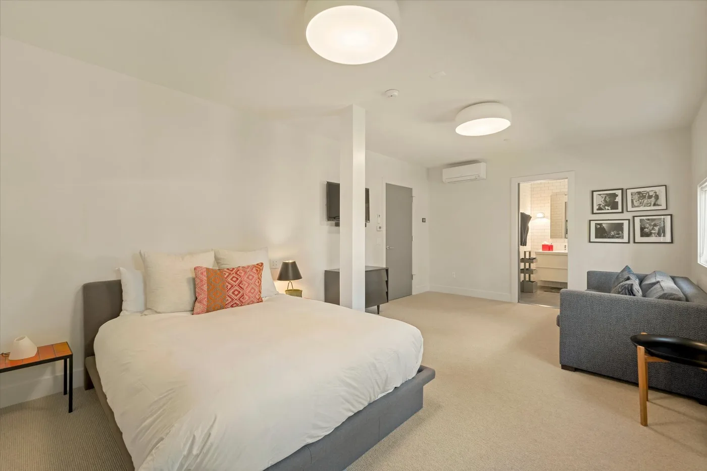 A bedroom with a neatly made bed and a seating area.