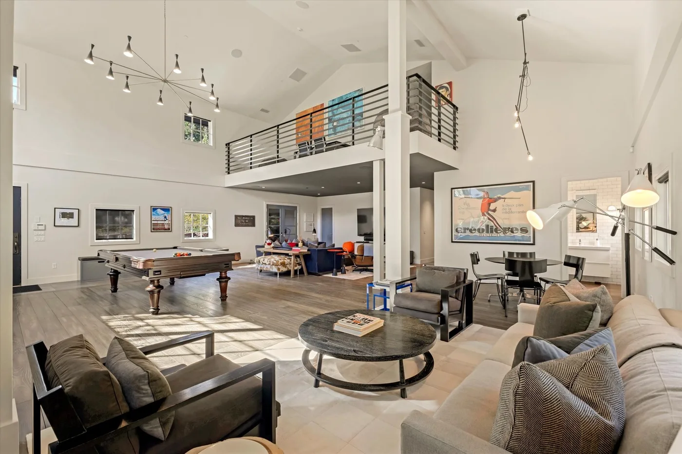 A spacious living room with seating, a pool table, and a dining area.