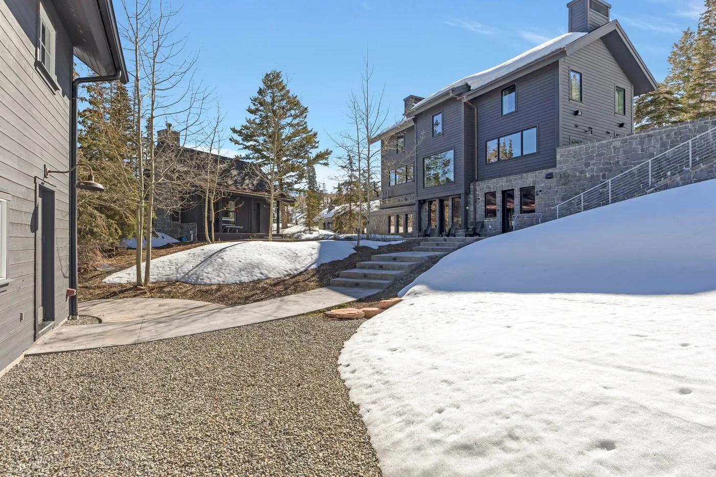 Snow-covered outdoor courtyard between buildings, with a gravel path and steps.