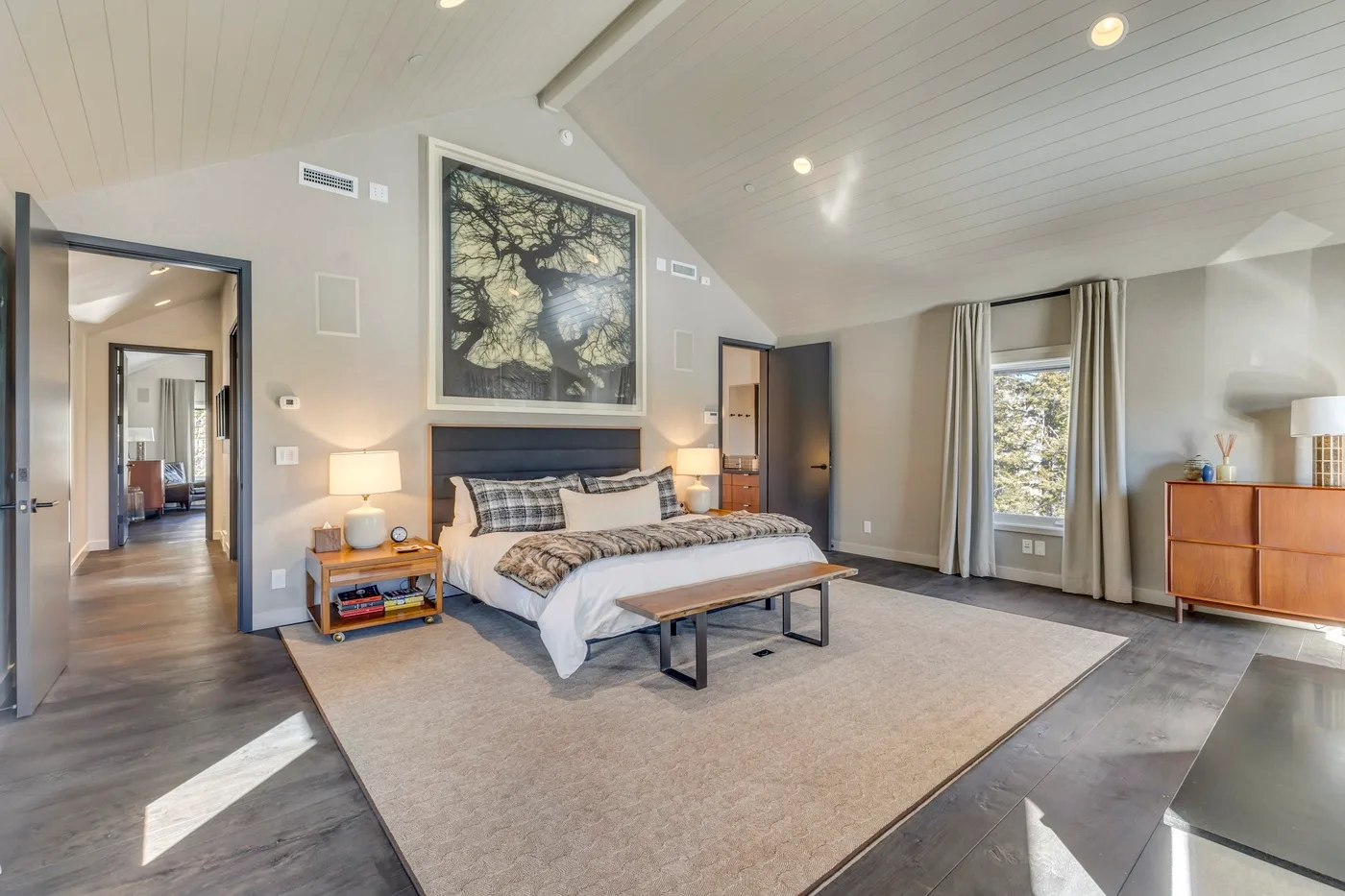 A bedroom with a bed, bedside tables, and a large rug.