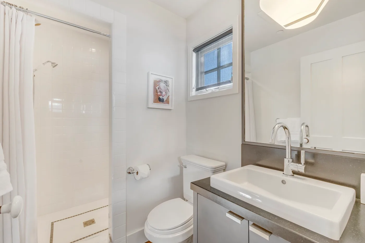 A bright bathroom with a sink, toilet, and shower.