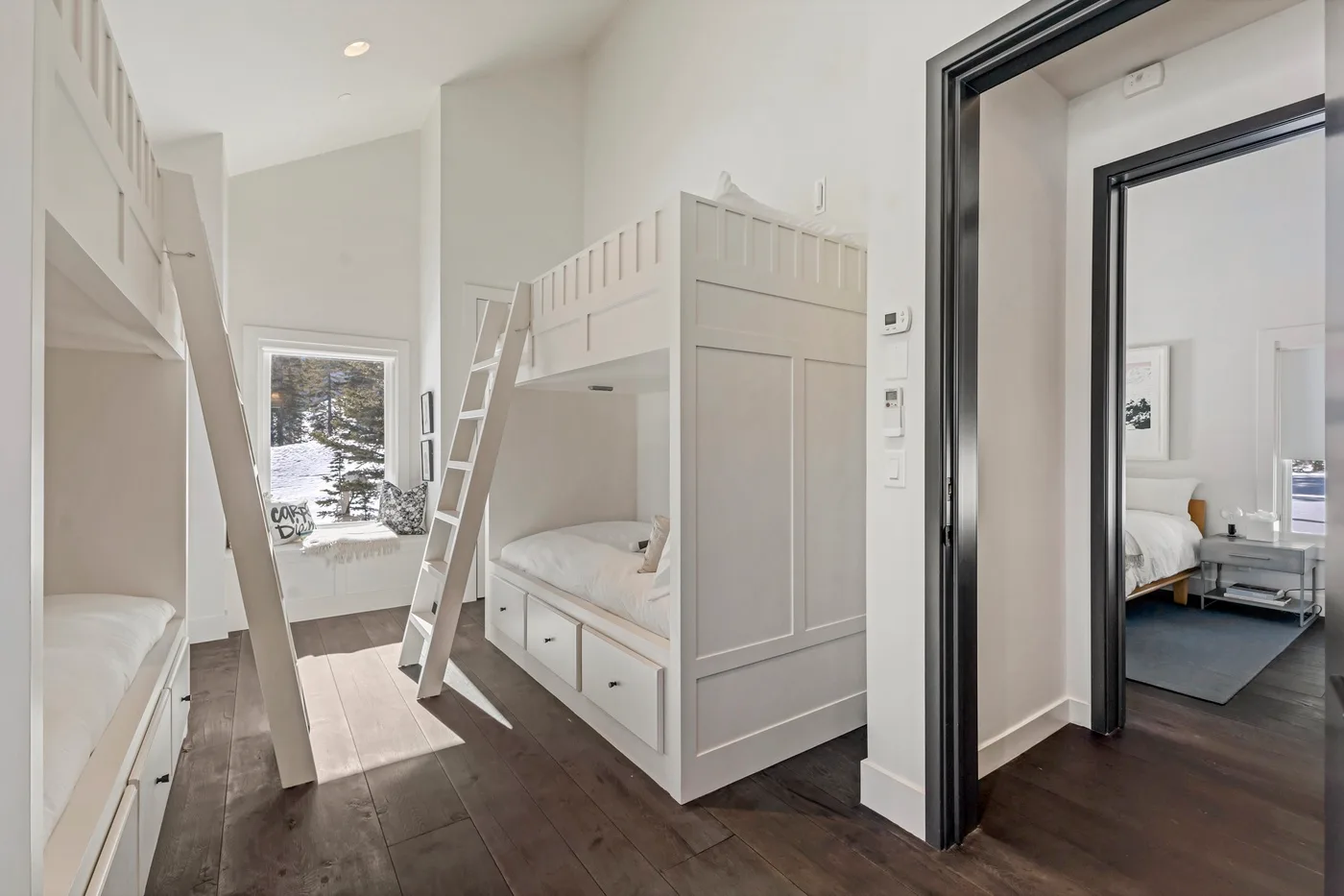 A bright bedroom with built-in bunk beds and a window overlooking snowy trees.