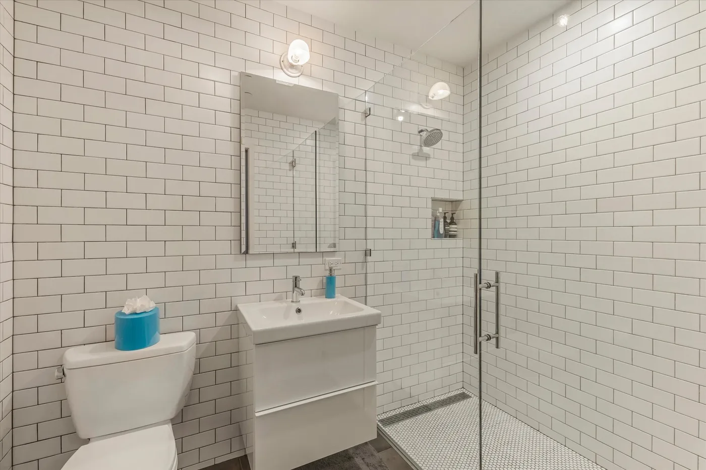 A tiled bathroom with a sink, mirror, and glass shower.