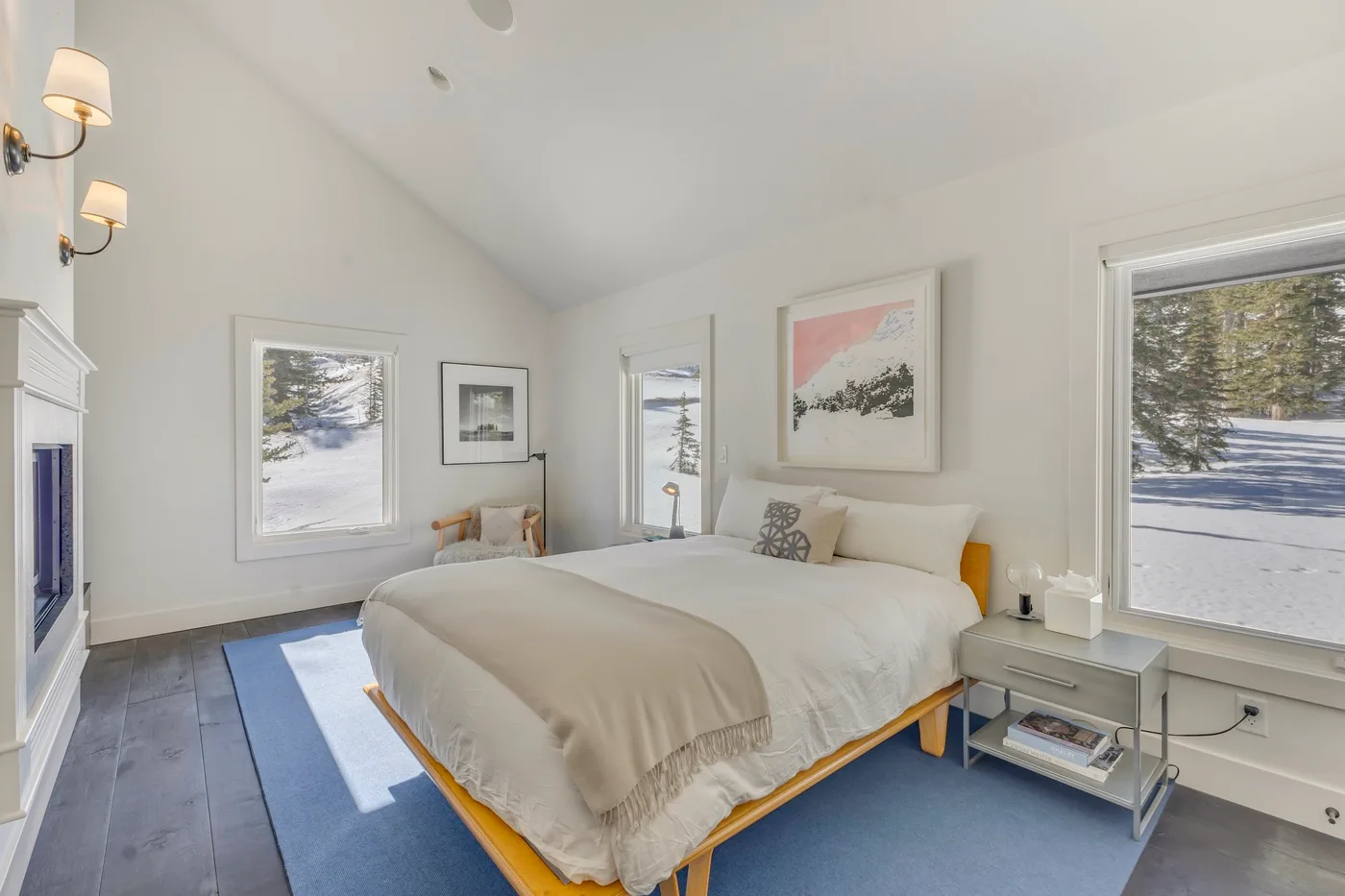 A bright bedroom with a large bed and snowy views through the windows.