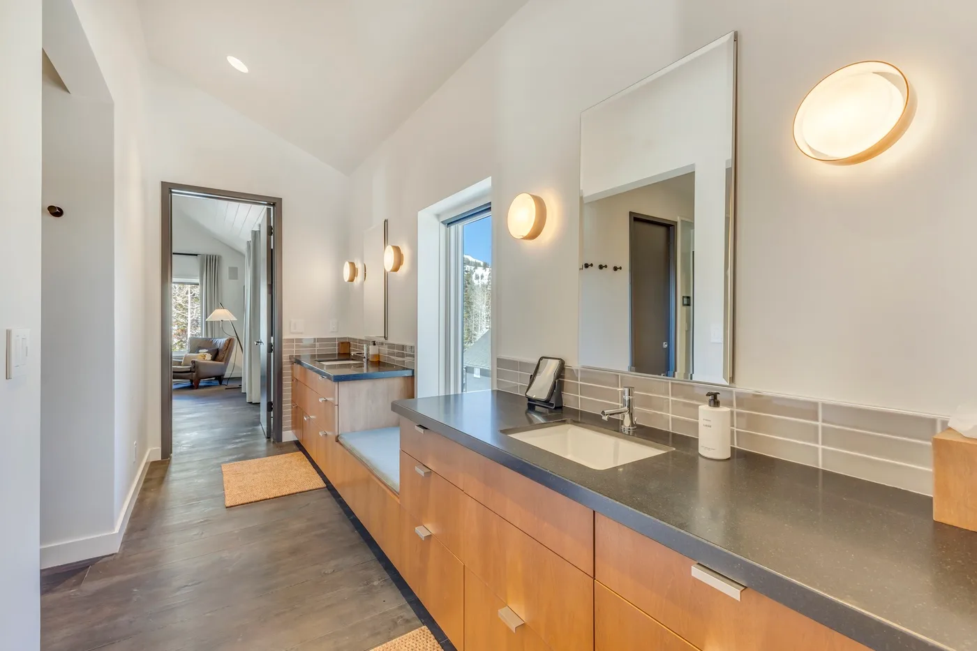 A bright bathroom with a long vanity, countertop sink, and large mirror.