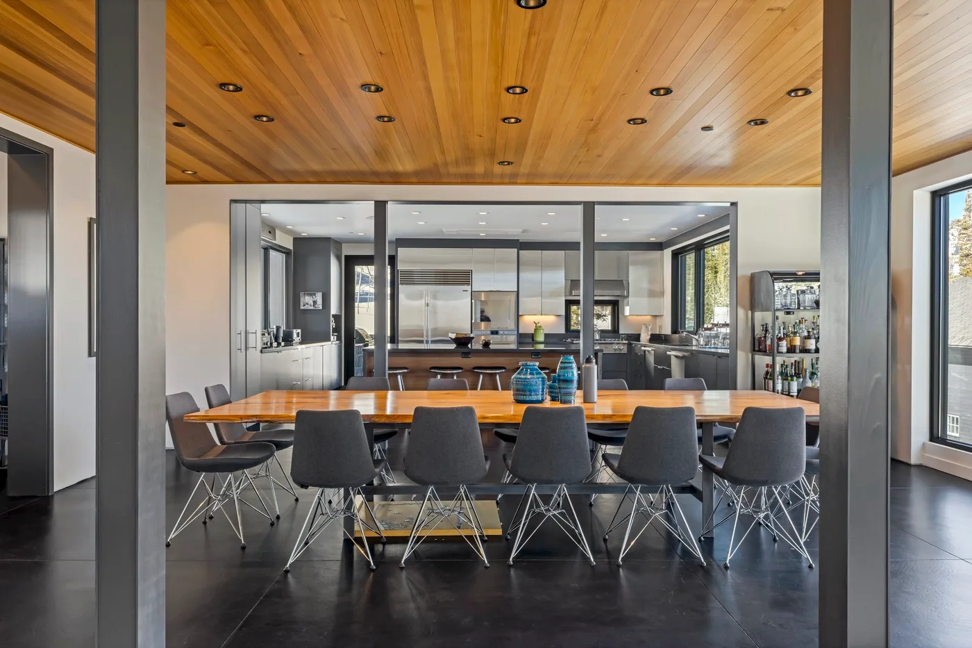 A dining area with a long table and seating beneath a wood-paneled ceiling.