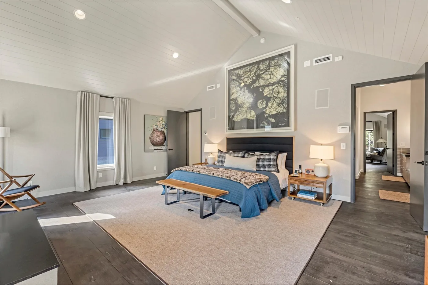A bedroom with a large bed, bedside tables, and a framed picture above the headboard.